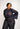 Person wearing a navy lace top and black pants on a white background