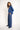 Woman wearing a blue outfit with a turtleneck sweater and striped pants on a white background