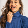 Woman wearing a blue turtleneck sweater against a white background
