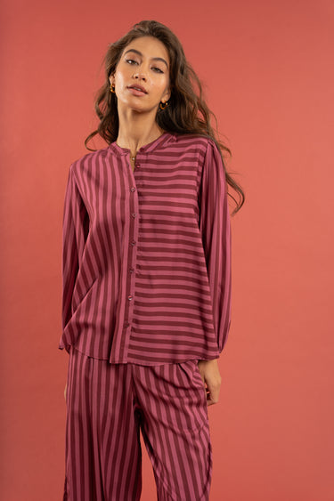 Woman wearing a maroon and pink striped outfit against a red background