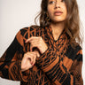 Woman wearing a patterned brown and black sweater against a white background
