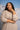 Woman in a beige sweater against a mountainous background