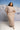 Woman wearing a beige dress with mountains in the background