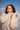 Woman wearing a beige sweater with a mountainous background
