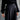 Person wearing a black outfit with wide-leg pants against a neutral background